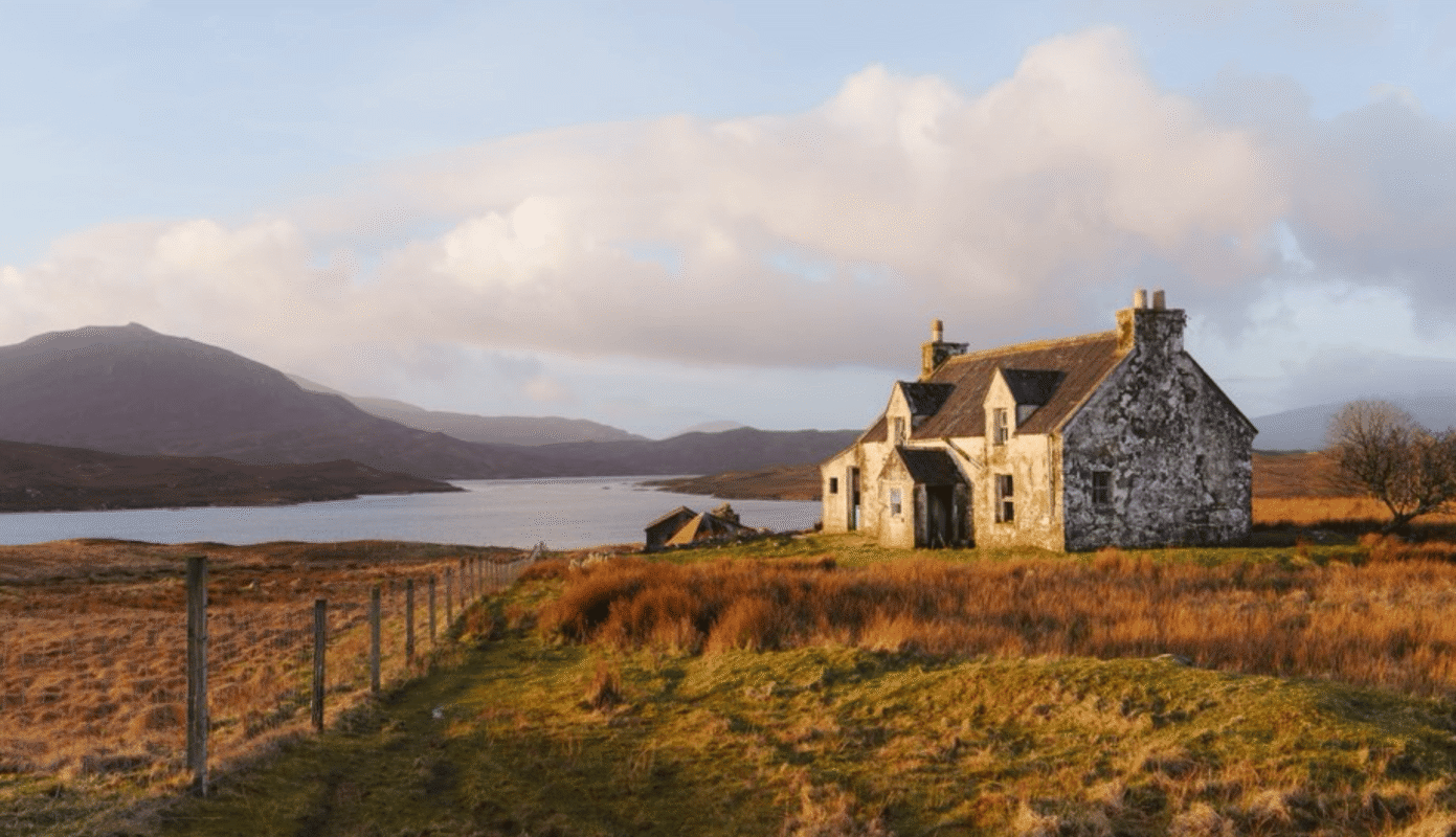 Weathered stone cottage beside a loch on the Isle of Lewis, Scotland, in golden autumn light
